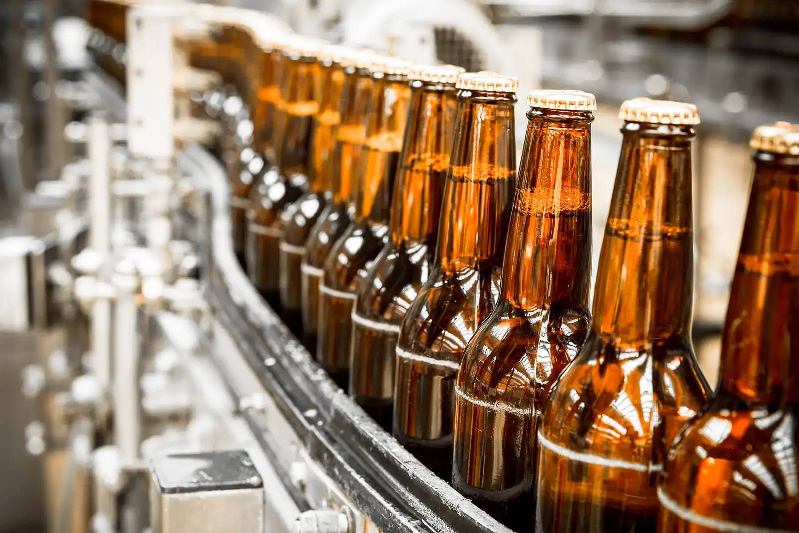 Barna üveges italok haladnak végig az ipari gyártósoron.